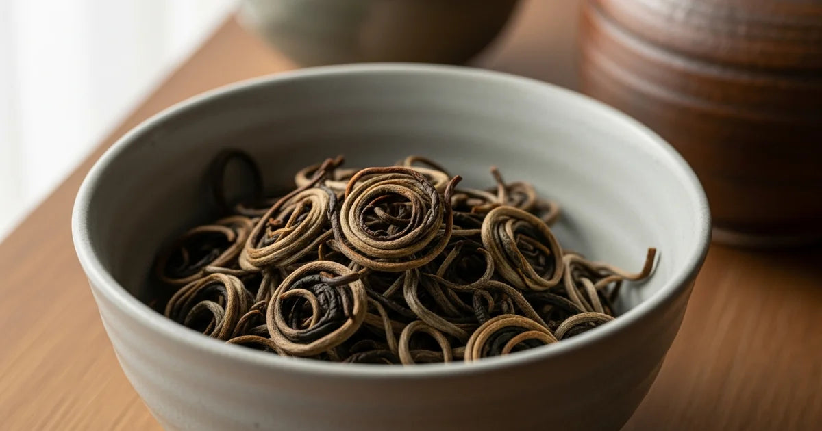 Pan-fired kamairicha green tea leaves with characteristic curl in a ceramic bowl