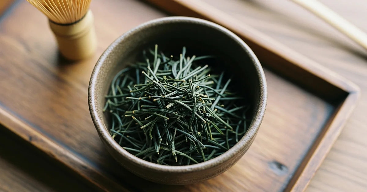 Gyokuro tea leaves, dark green thin needles in a small Japanese ceramic cup