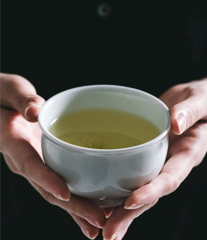 A cup of green tea held in both hands