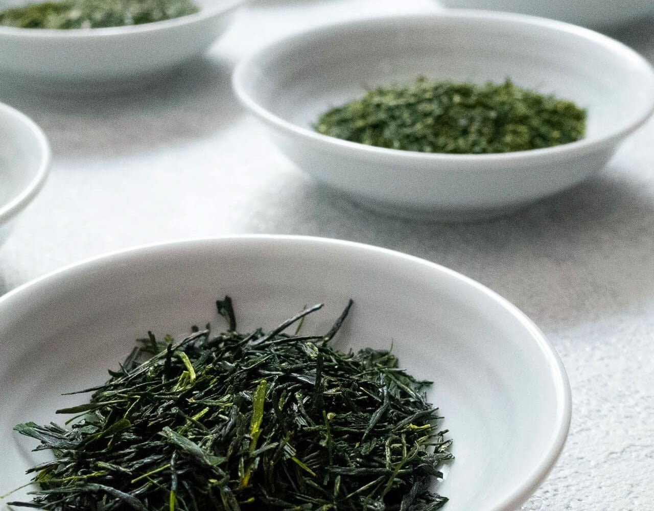 Loose leaf teas laid out in white tasting bowls